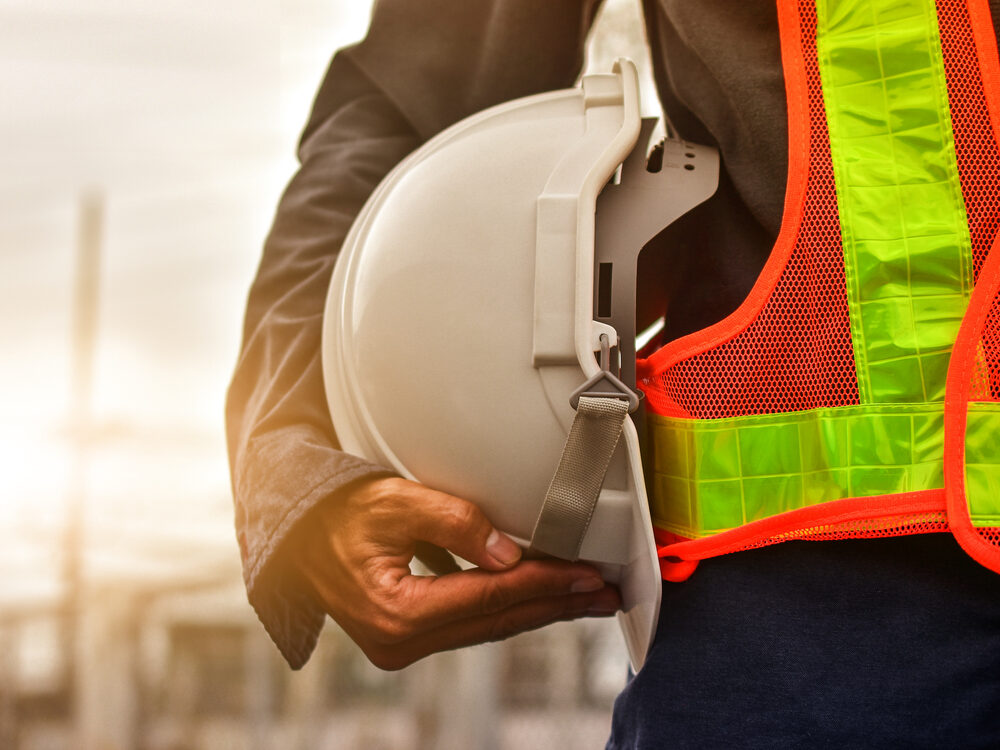 Technician holding white hat safety hard hat sunlight background